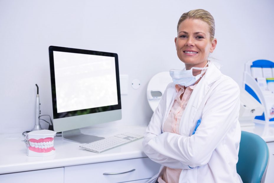 Dentista sorrindo na frente dos softwares odontológicos