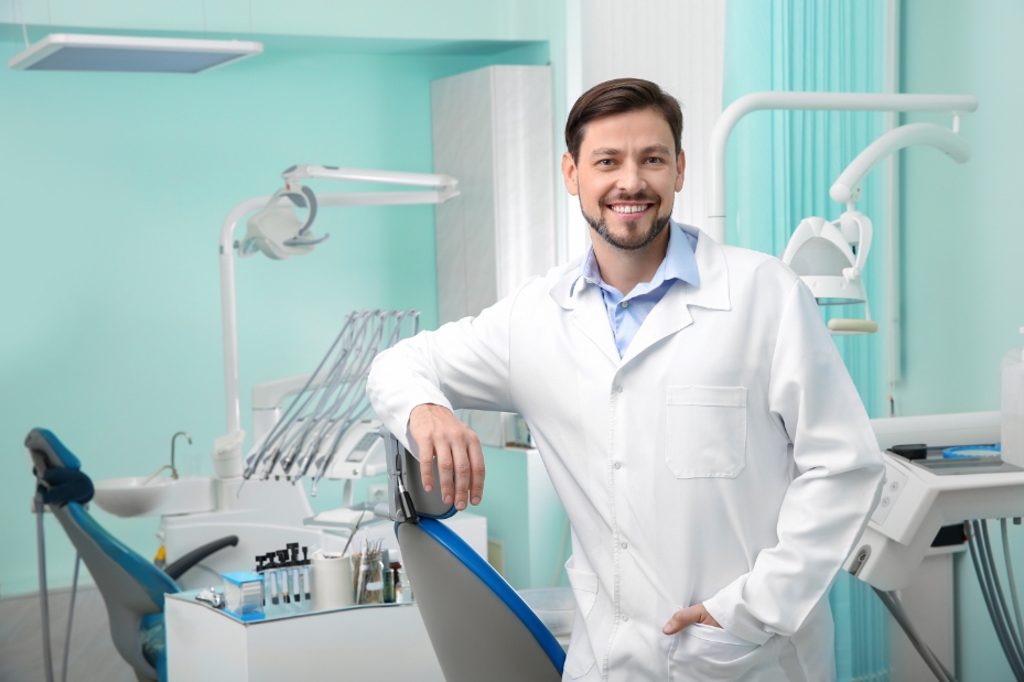 dentista sorrindo em seu consultório odontológico